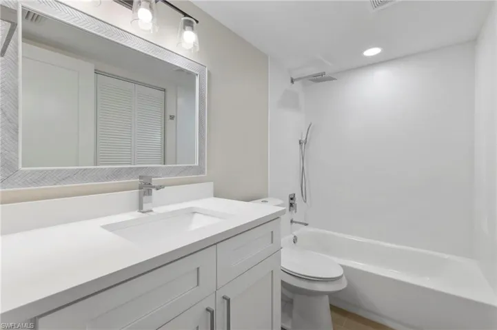 Bathroom featuring vanity, shower / tub combination, a closet, and recessed lighting