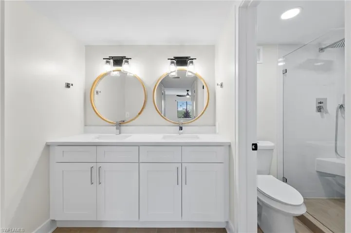 Bathroom featuring double vanity, a shower stall, and light wood-type flooring