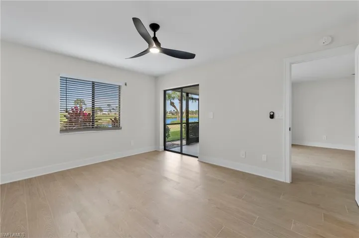 Empty room featuring light wood-type flooring, a ceiling fan, and a water view