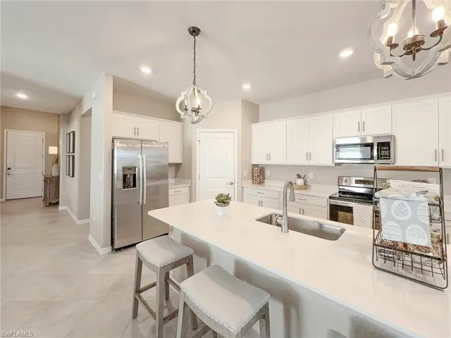 Kitchen featuring a chandelier, appliances with stainless steel finishes, a breakfast bar, white cabinetry, and recessed lighting