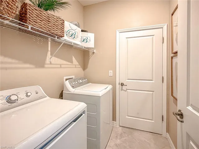 Washroom featuring washing machine and clothes dryer and light tile patterned floors
