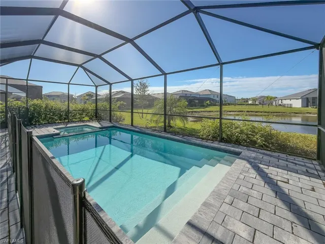 View of swimming pool featuring a sunroom, a lanai, a pool with connected hot tub, a residential view, and a water view