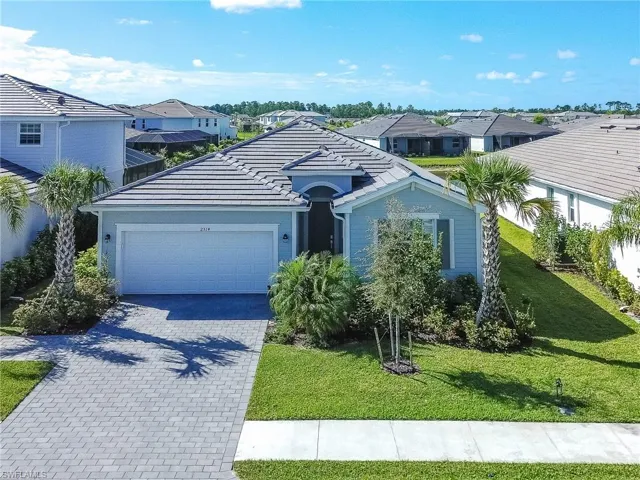 View of front of house featuring a residential view, decorative driveway, and a front lawn