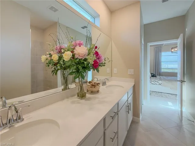 Bathroom with light tile patterned floors, double vanity, ensuite bathroom, and tiled shower