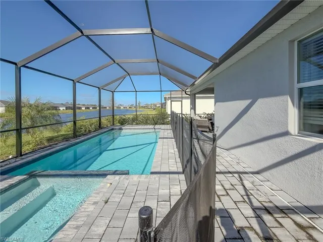 View of swimming pool featuring a lanai, a pool with connected hot tub, a sunroom, and a water view