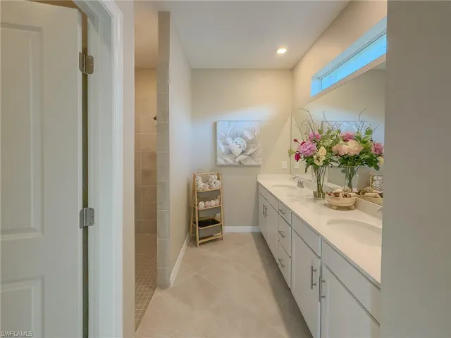 Full bath with double vanity, light tile patterned floors, walk in shower, and recessed lighting