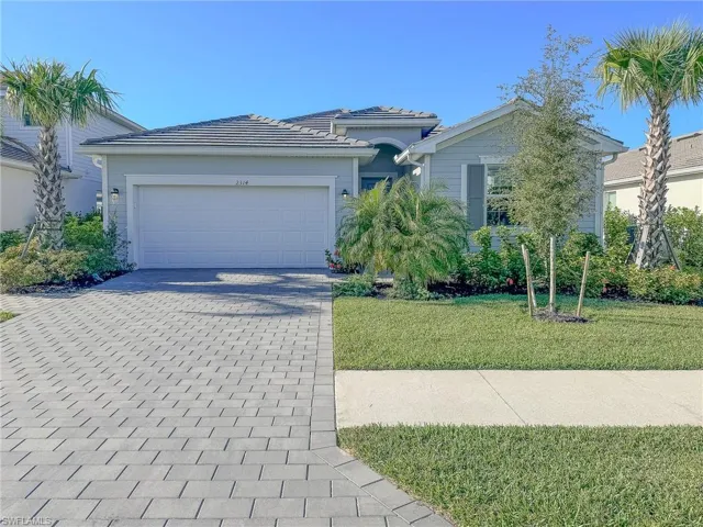 Ranch-style house featuring a front lawn, decorative driveway, an attached garage, and a tiled roof