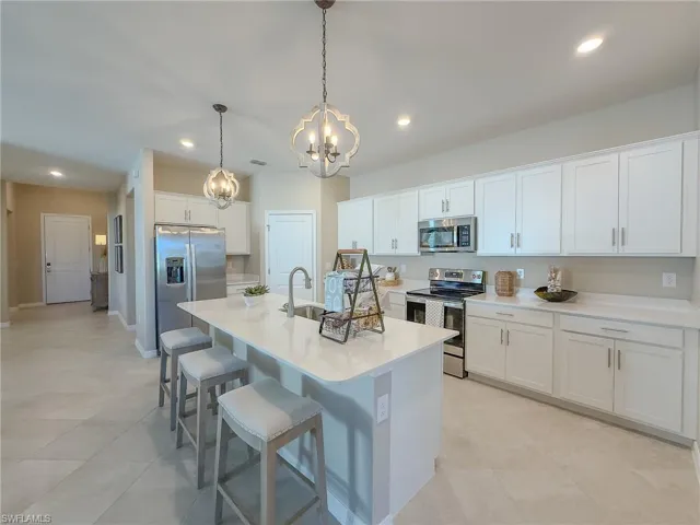 Kitchen featuring appliances with stainless steel finishes, a kitchen breakfast bar, recessed lighting, white cabinetry, and decorative light fixtures