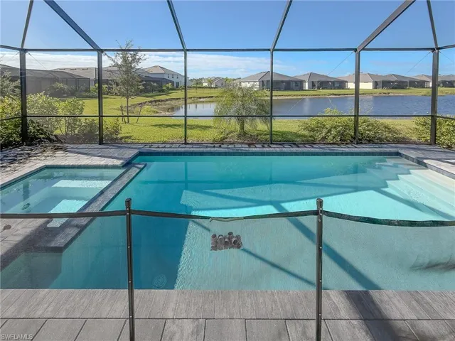 View of pool featuring a sunroom, a water view, a residential view, a lanai, and a pool with connected hot tub