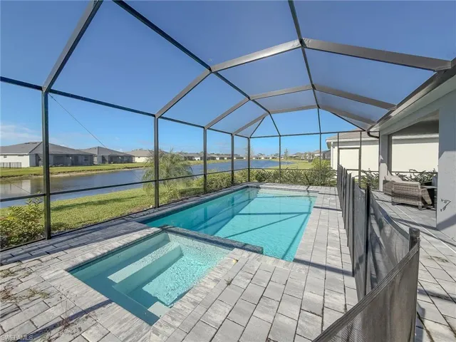 View of pool with a water view, a sunroom, a pool with connected hot tub, a lanai, and a residential view