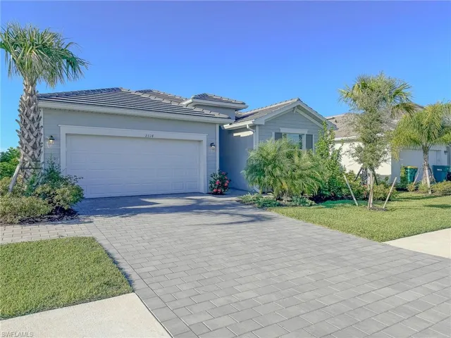 View of front of property with decorative driveway, a garage, a front yard, and a tiled roof