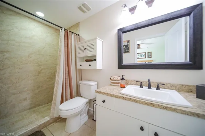The Master Bathroom featuring tile patterned floors, a shower with curtain, vanity, and toilet!