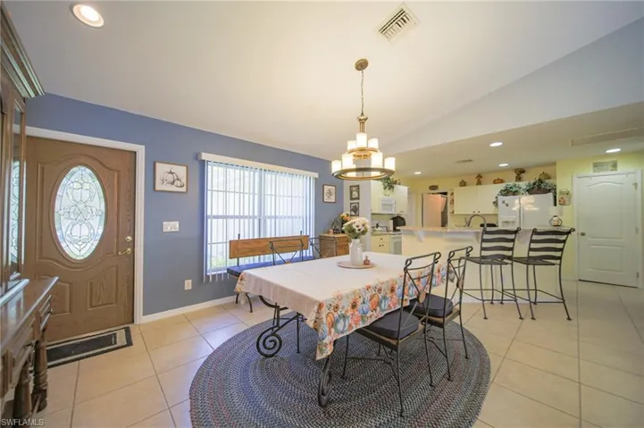Tiled dining space with a notable chandelier and vaulted ceiling