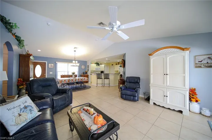 Tiled living room featuring ceiling fan and vaulted ceiling