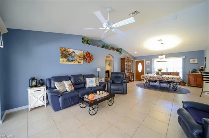 Tiled living room featuring lofted ceiling and ceiling fan