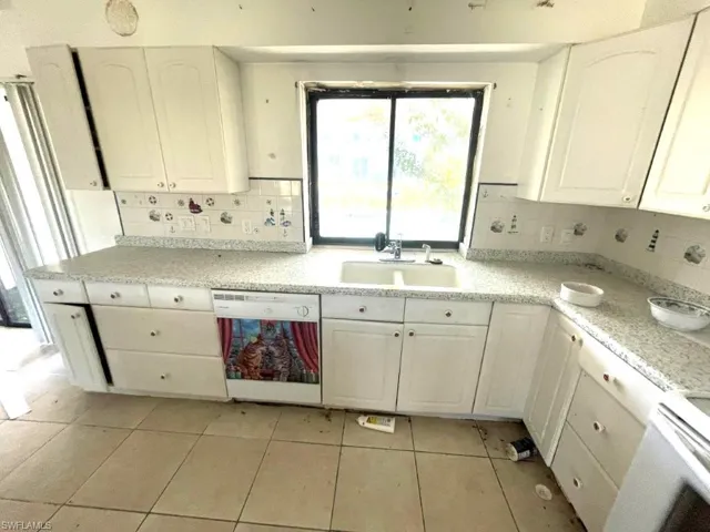 Kitchen featuring white cabinetry with arch panel doors and light-colored countertops