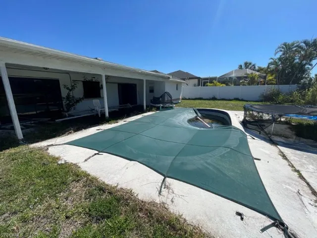Concrete patio surrounding an inground swimming pool with a dark green safety cover