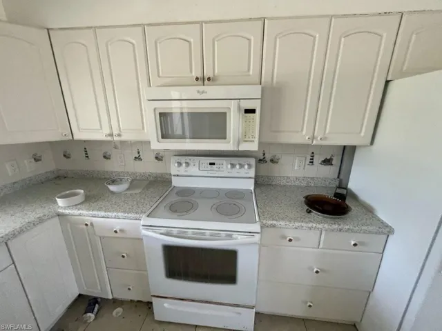Kitchen featuring white cabinetry, light-colored countertops, a white electric range, and an over-the-range microwave
