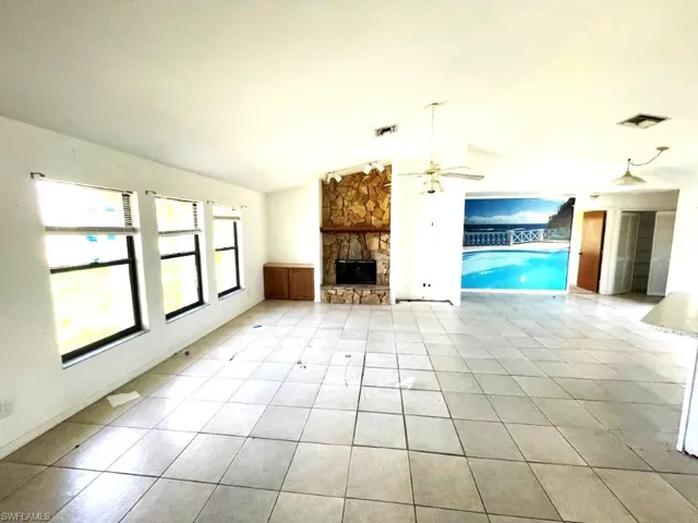 Spacious interior featuring tile flooring, a stone fireplace, multiple windows, and a built-in wall mural