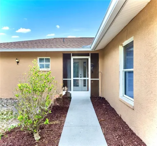 Property entrance featuring stucco siding and a shingled roof