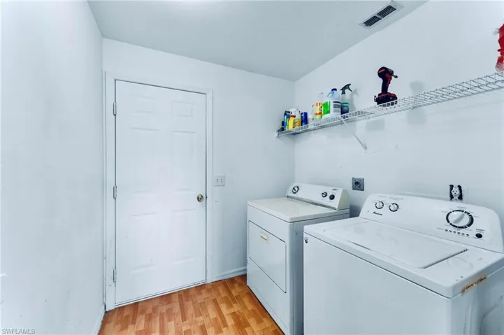 Laundry area featuring washing machine and dryer, light wood finished floors, and baseboards