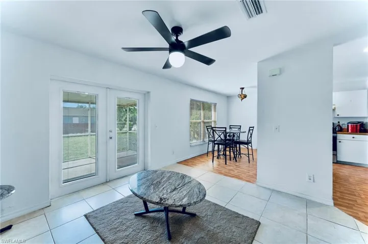 Living area featuring french doors, light tile patterned flooring, ceiling fan, and baseboards