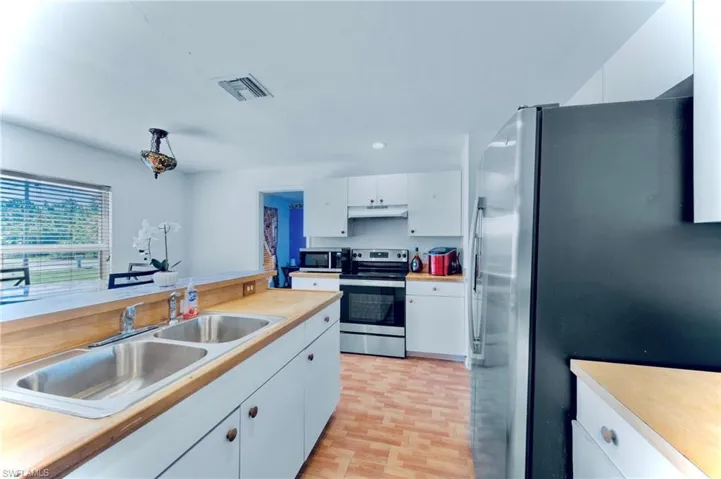 Kitchen featuring stainless steel appliances, under cabinet range hood, a sink, light countertops, and recessed lighting