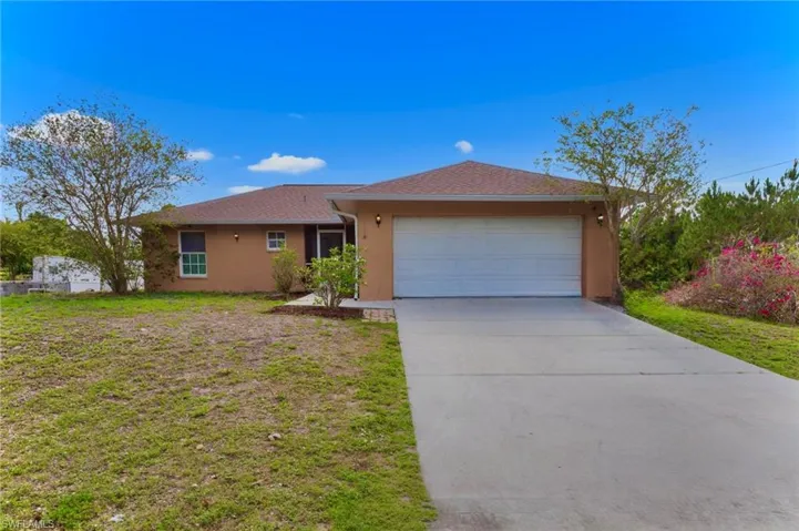 Ranch-style home featuring stucco siding, an attached garage, concrete driveway, and a front lawn