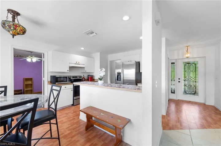 Kitchen featuring stainless steel appliances, white cabinetry, under cabinet range hood, recessed lighting, and light wood-type flooring