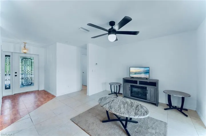 Living area featuring tile patterned floors, a ceiling fan, and baseboards