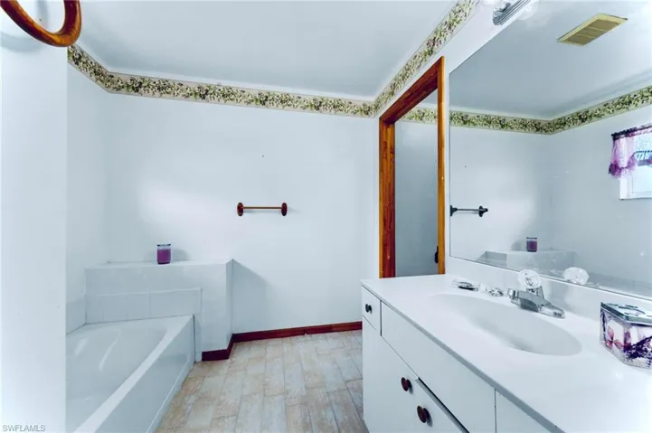 Full bathroom featuring vanity, a garden tub, and baseboards