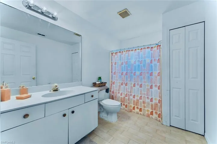 Full bath featuring a closet, vanity, and toilet