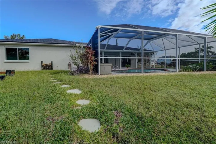 Rear view of property with a yard and a lanai