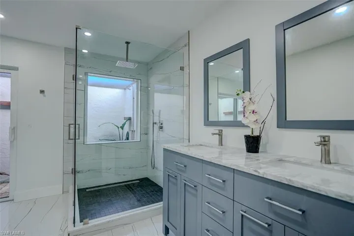 Bathroom with vanity, a shower with shower door, and plenty of natural light