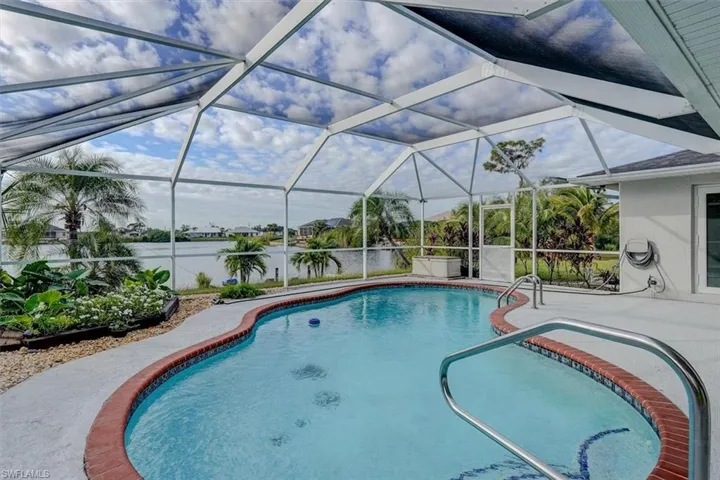 View of swimming pool with glass enclosure, a water view, and a patio