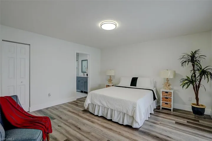 Bedroom with wood-type flooring, connected bathroom, and a closet