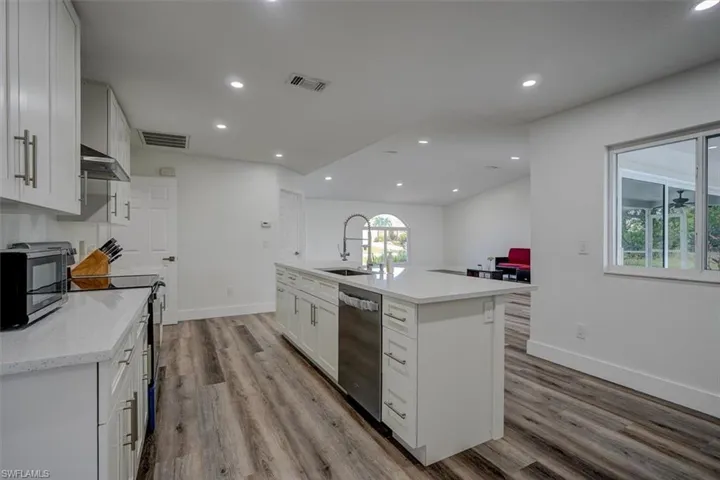 Kitchen featuring white cabinetry, sink, light hardwood / wood-style flooring, a kitchen island with sink, and appliances with stainless steel finishes