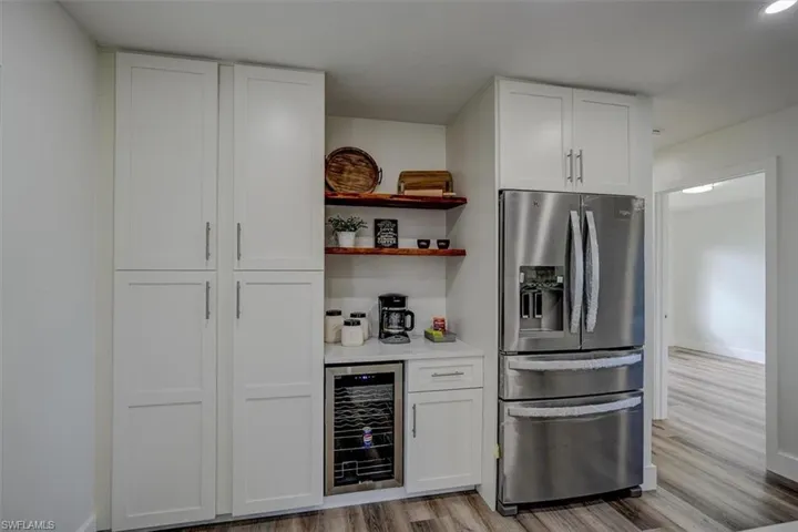 Kitchen featuring white cabinetry, light wood-type flooring, wine cooler, and stainless steel fridge with ice dispenser