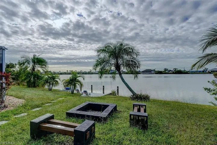 Surrounding community with a water view and a lawn