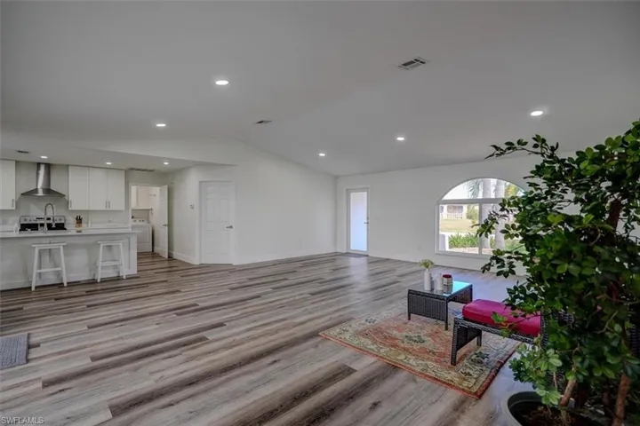 Living room featuring sink, light hardwood / wood-style floors, and vaulted ceiling