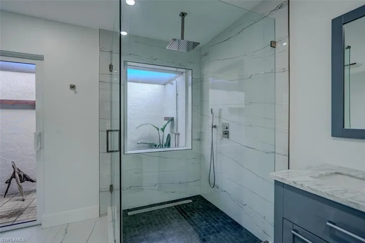 Bathroom featuring a shower with door, vanity, and lofted ceiling