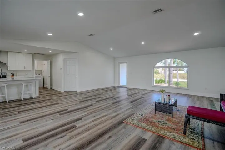 Living room featuring sink, washer / dryer, lofted ceiling, and light hardwood / wood-style floors