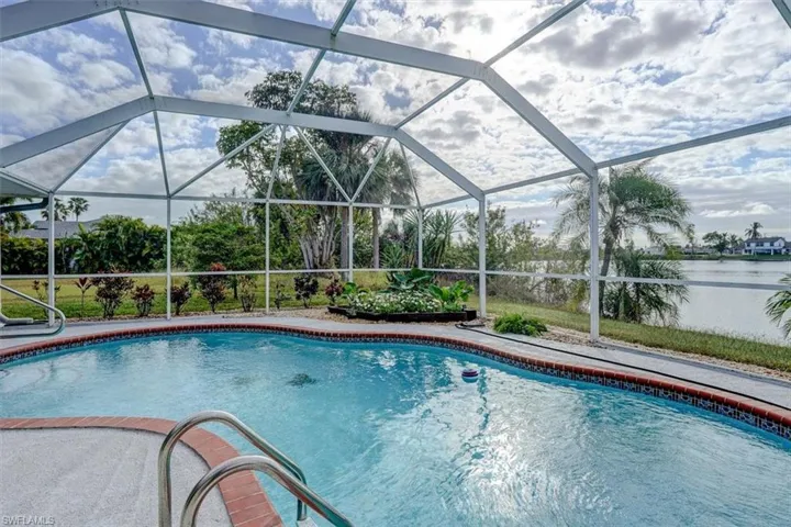 View of swimming pool featuring glass enclosure and a water view
