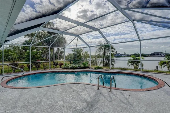View of swimming pool featuring glass enclosure and a water view