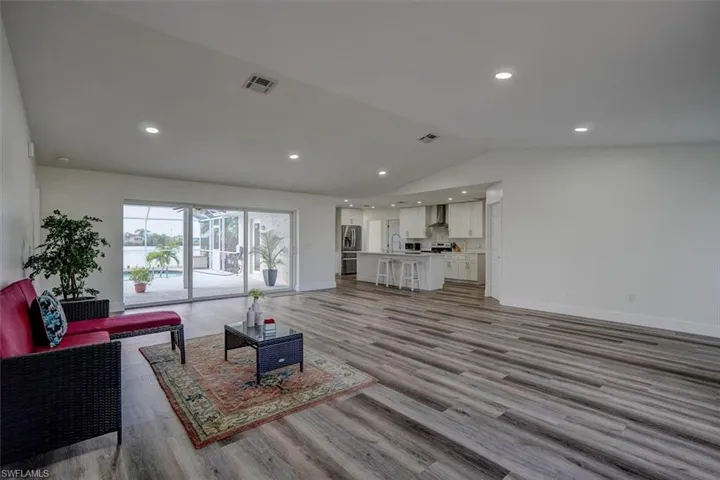 Living room with light hardwood / wood-style flooring, sink, and lofted ceiling
