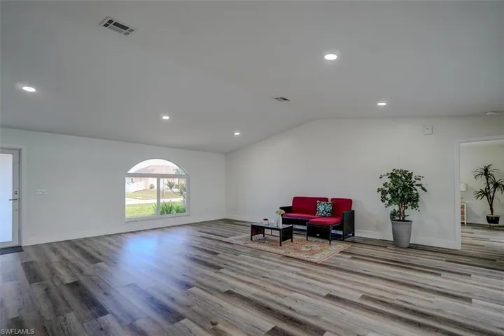Unfurnished room with light hardwood / wood-style flooring and lofted ceiling
