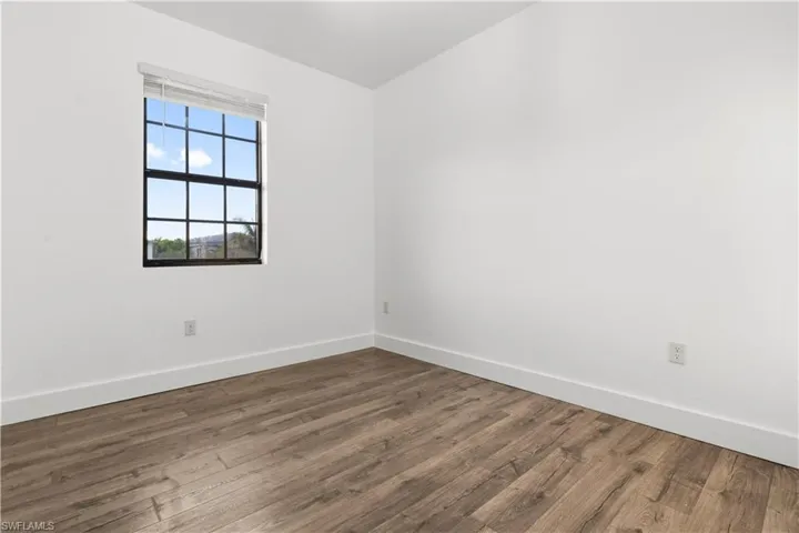 Spare room featuring baseboards and dark wood-style floors