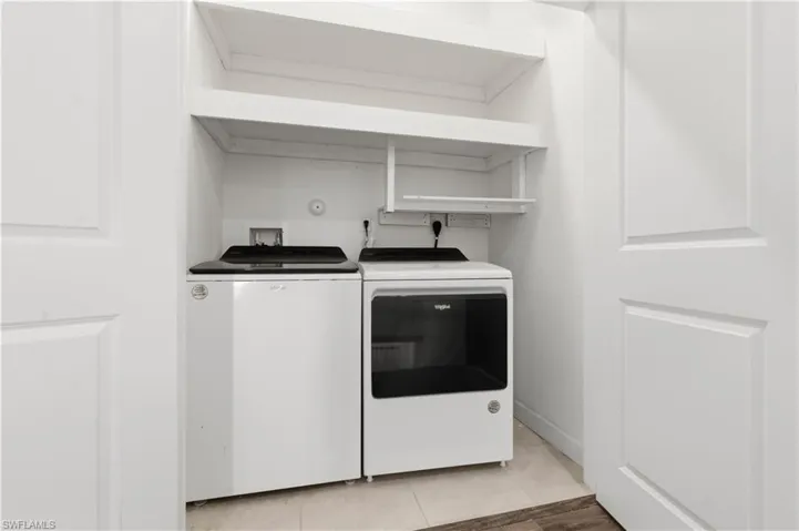 Laundry area with light tile patterned floors and washing machine and dryer