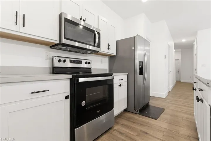 Kitchen with stainless steel appliances, white cabinetry, light wood finished floors, light countertops, and recessed lighting