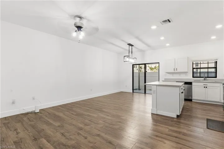 Kitchen featuring a center island, white cabinets, light countertops, hanging light fixtures, and dark wood finished floors